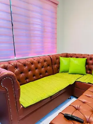 a brown leather couch with two green pillows on it at Von Home Sweet Home in Dasmariñas