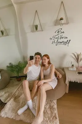a man and a woman sitting on a couch with a cell phone at YourSafeHaven Calathea Place Lavender Bldg in Manila