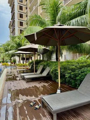 a patio with benches and umbrellas on a beach at YourSafeHaven Calathea Place Lavender Bldg in Manila