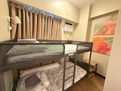 a bunk bed in a small room with a window at Aesthetic Cozy Modern Condo Apartment in Manila