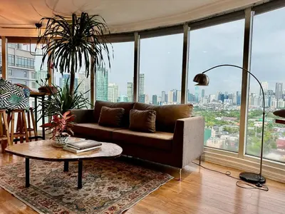 a living room with a couch and a large window at 55-SQM Stunning View Wood House Poblacion Makati in Manila