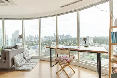 an office with a desk and chairs and windows at 55-SQM Stunning View Wood House Poblacion Makati in Manila