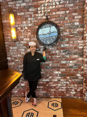 a woman standing in front of a brick wall with a clock at Homesweethome Beach Resort in Manila