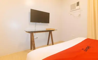 a bedroom with a desk with a television on a wall at RedDoorz at Zenova Hotel in Manila