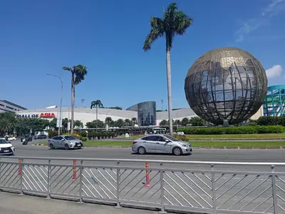 two cars driving down a road in front of a large sphere at V&G Era Staycation in Manila