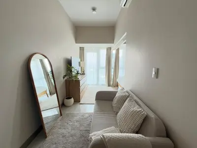 a living room with a couch and a mirror at Uptown Suites in Manila