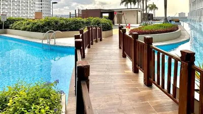 a swimming pool with a walkway next to a building at Cozy accommodation near MOA AIRPORT WORLD TRADE AND PICC in Manila