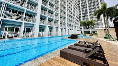 a swimming pool with chaise lounges next to a building at Cozy accommodation near MOA AIRPORT WORLD TRADE AND PICC in Manila