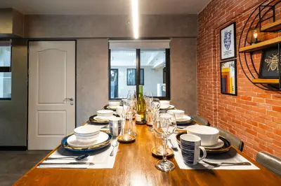 a long wooden table with plates and glasses on it at Boutique one-bedroom apartment near airport, business hubs in Manila