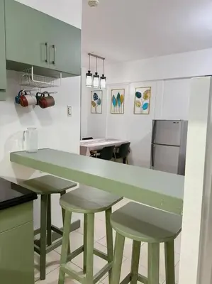 a kitchen with a green counter and two stools at Apartment in Parañaque in Manila