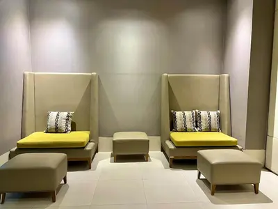 two chairs with yellow cushions in a waiting room at Chic 1-BR at Uptown BGC in Manila