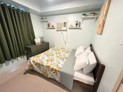 a small bedroom with a bed and a fan at A & M SUITE VACAY - Sea Residences Mall Of Asia Pasay in Manila