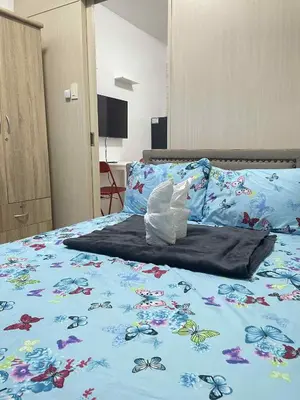 a bed with a blue comforter with glasses on it at Vonz Staycation Near Moa in Manila