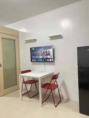 a white table with two red chairs and a black refrigerator at Vonz Staycation Near Moa in Manila