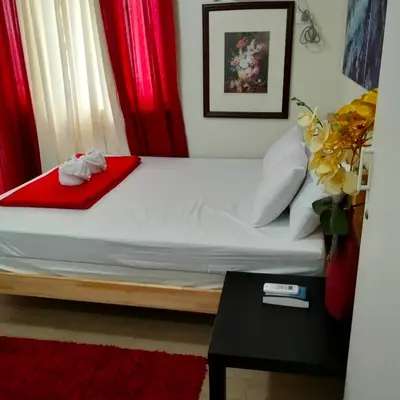 a bedroom with a bed with red curtains and a table at Cozy Gutz Place at 16th in Manila