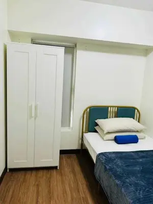 a bedroom with a bed and a white cabinet at Vtan Condo in Manila