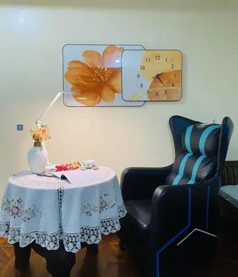 a table and a chair with a table and a clock at Stan Condo in Manila