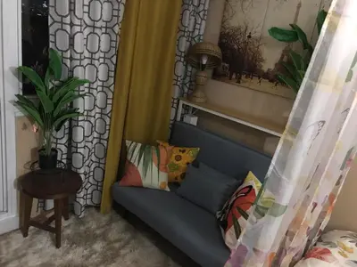 a blue couch with pillows in a living room at Cosy Studio with balcony 100mbps and Netflix in Manila