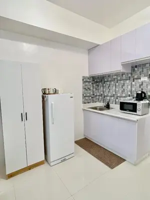 a white kitchen with a refrigerator and a sink at Studio Unit at Grand Riviera Suites in front of US Embassy in Manila