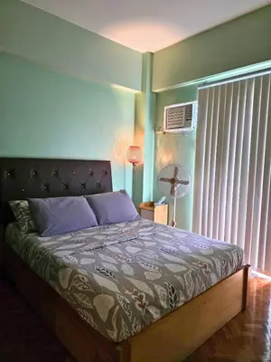 a bedroom with a bed and a window with a fan at Home of Poli - 1BR with FREE Netflix & WiFi in Manila