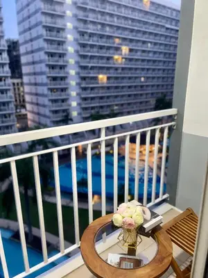 a table with a vase of flowers on a balcony at Cozy Place at Shell Residences in Manila