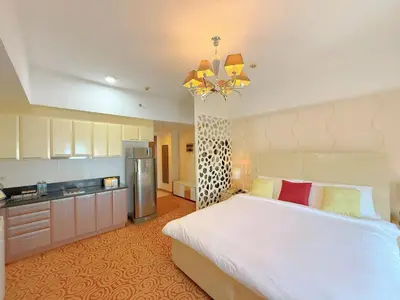 a bedroom with a large white bed and a refrigerator at MaxStays - Max Home at The Venice Residences in Manila