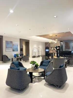 a lobby with chairs and a table and a kitchen at staycation condo one bedroom balcony w pool view near SMX SM MOA IKEA NAIA DFA OCEAN PARK in Manila