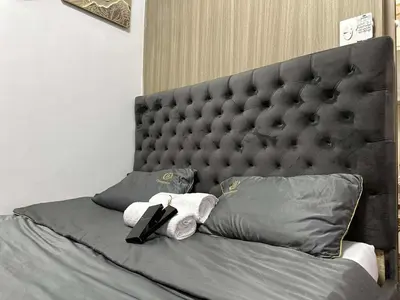 a bed with a large padded headboard in a bedroom at STAYCATION CONDO SHORE RESIDENCES one bedroom w balcony pool view near SMX SM MOA IKEA NAIA DFA OCEAN PARK DFA in Manila