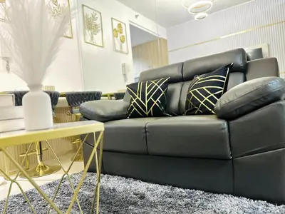 a living room with a black couch and a table at STAYCATION CONDO SHORE RESIDENCES one bedroom w balcony pool view near SMX SM MOA IKEA NAIA DFA OCEAN PARK DFA in Manila