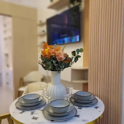 a table with plates and a vase with flowers on it at Fourth's Jazz Cozy Pad in Manila
