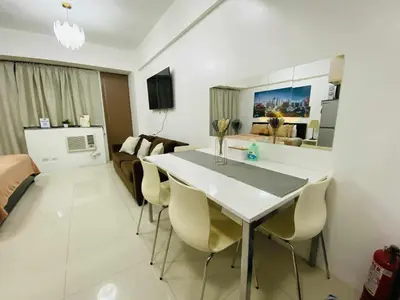 a kitchen and living room with a table and chairs at Bekipay Suite at One Palm Tree right across NAIA 3 in Manila