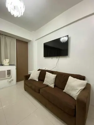 a living room with a brown couch and a tv at Bekipay Suite at One Palm Tree right across NAIA 3 in Manila