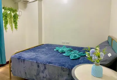 a room with a bed with a table and a vase of flowers at Vtan Condo in Manila