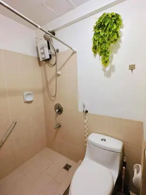 a bathroom with a toilet and a green plant on the wall at Arista place staycation in Manila