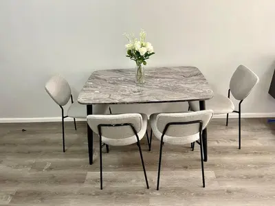 a table with chairs and a vase of flowers on it at Nyli Minimalist Suite in Manila
