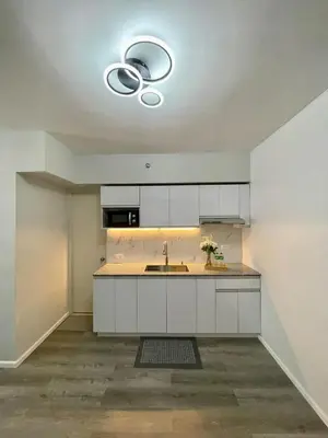 an empty kitchen with white cabinets and a sink at Nyli Minimalist Suite in Manila