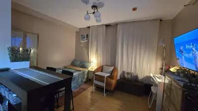 a living room with a television and a room with a bed at Metrotowne PHINMA Las Pinas in Manila