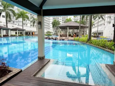 a large swimming pool with blue water in a building at PinkdoorZ Moa Staycation at Shell Residences in Manila