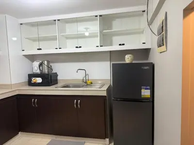 a kitchen with a sink and a black refrigerator at California Gardens square in Manila