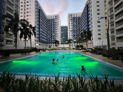 a group of people in a swimming pool with buildings at Suite Haven - Sea Residences MOA PASAY in Manila