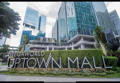 a sign in front of a city with tall buildings at One Uptown Residence BGC 1BR sofabed in Manila