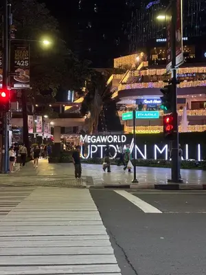 a city street at night with a large sign on a building at One Uptown Residence BGC 1BR sofabed in Manila
