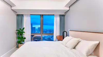 a bedroom with a bed and a large window at Private Apartment walk to Greenbelt, Legazpi Village in Manila