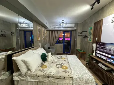 a bedroom with a bed and a flat screen tv at Balai Bacasionan - Sea Residences MOA Pasay in Manila