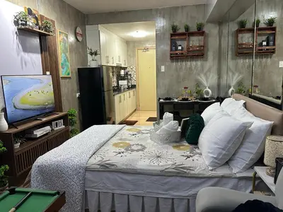 a room with a bed with a television and a kitchen at Balai Bacasionan - Sea Residences MOA Pasay in Manila