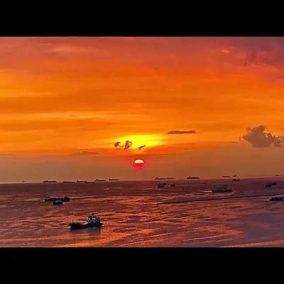 a sunset over the ocean with boats in the water at Place To Stay Near US Embassy Front Of Manila Bay in Manila