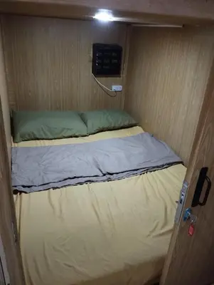 a small bed in a small room with a door at Capsule bed in Manila