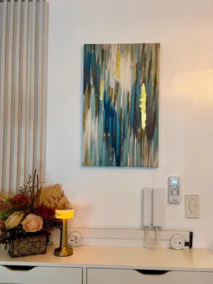 a painting on a wall above a desk with a lamp at Infinity Suites Makati in Manila