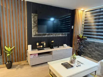 a living room with a tv on a wall at 2 bedroom loft type with 2 baths Near Ortigas Cbd in Manila