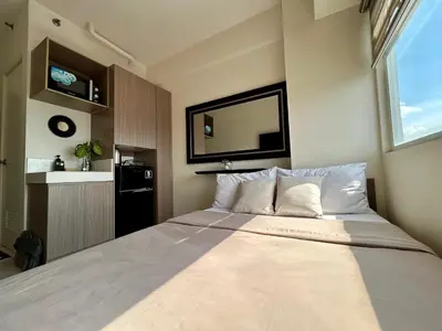 a bedroom with a large bed with a large window at NIJECRIFIL Condotel in Manila
